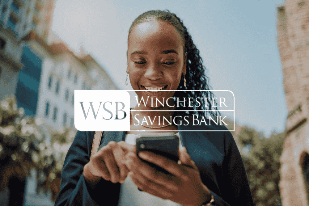 Woman looking down at her phone image with Winchester Savings Bank logo is overlayed