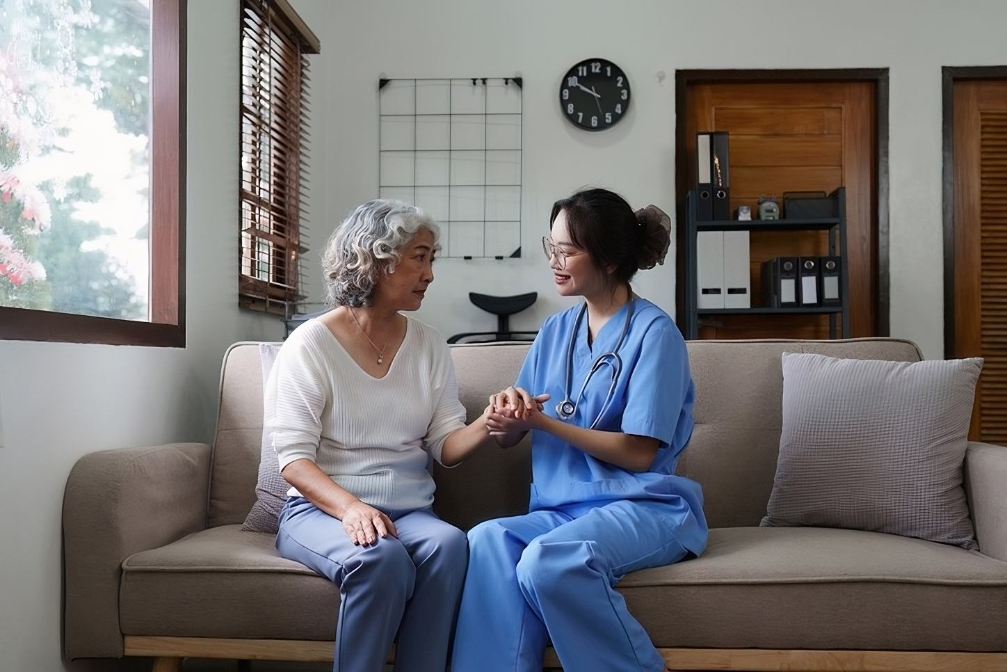 Nurse holding a patient's hand while sitting on a couch