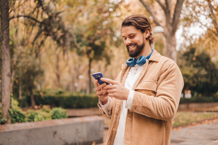 man smiling while looking at his cell phone