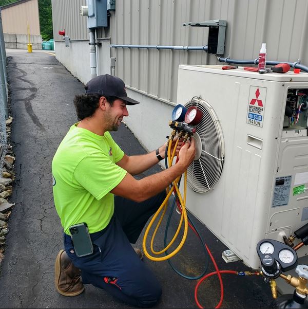 man fixing air conditioning unit with tools