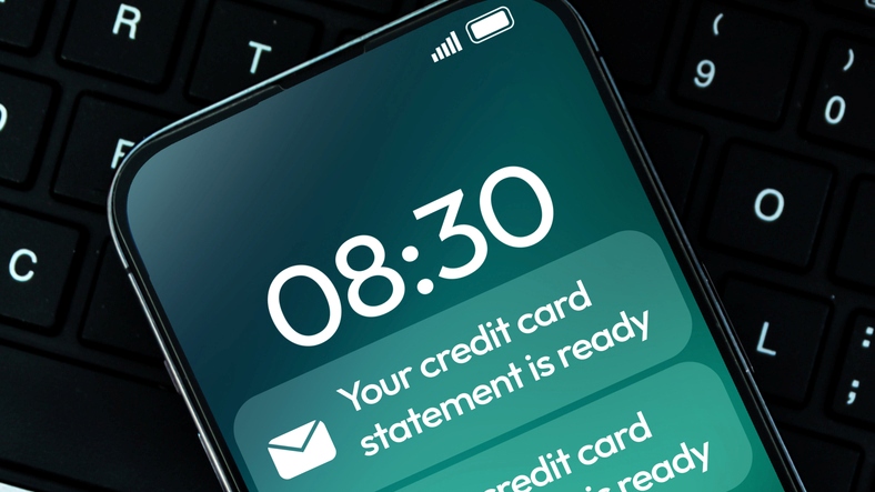 Credit card statement ready notification appearing on the smartphone with keyboard in the backdrop, banking and finance concept